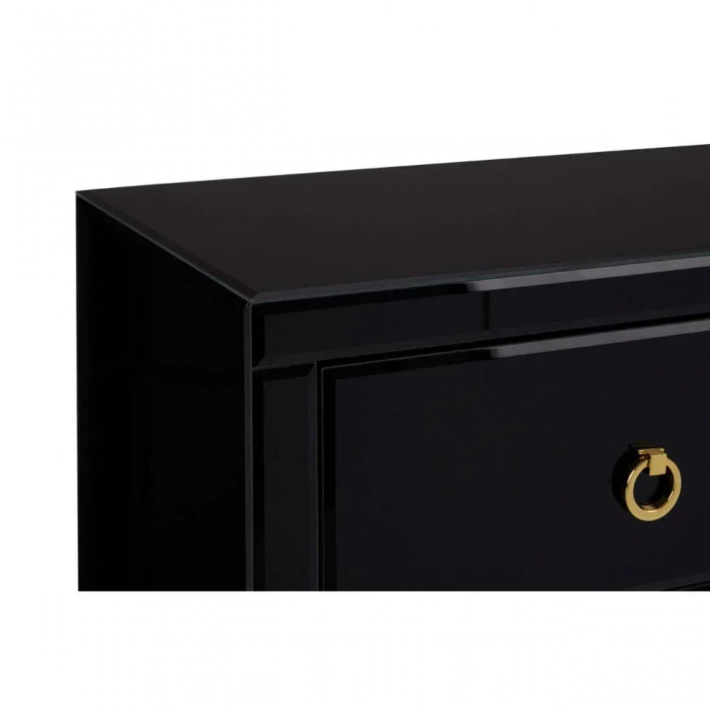 Glossy black chest of drawers with gold ring handle, close-up of corner and drawer front