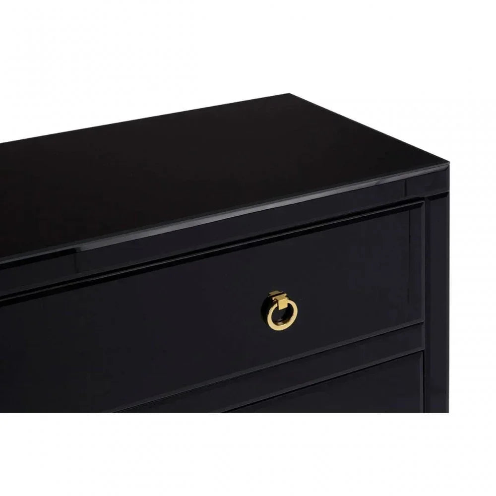Black chest of drawers with gold metal ring handle, close-up of top drawer corner