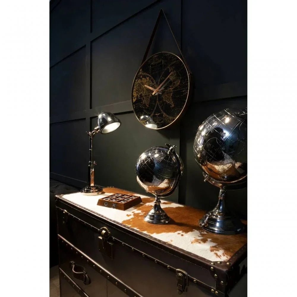 Metal desk globes and a map wall clock on vintage storage trunk with table lamp