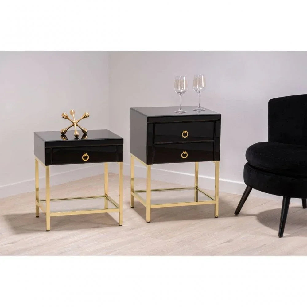 Black gloss bedside tables with gold metal frames and drawer pulls beside a velvet chair
