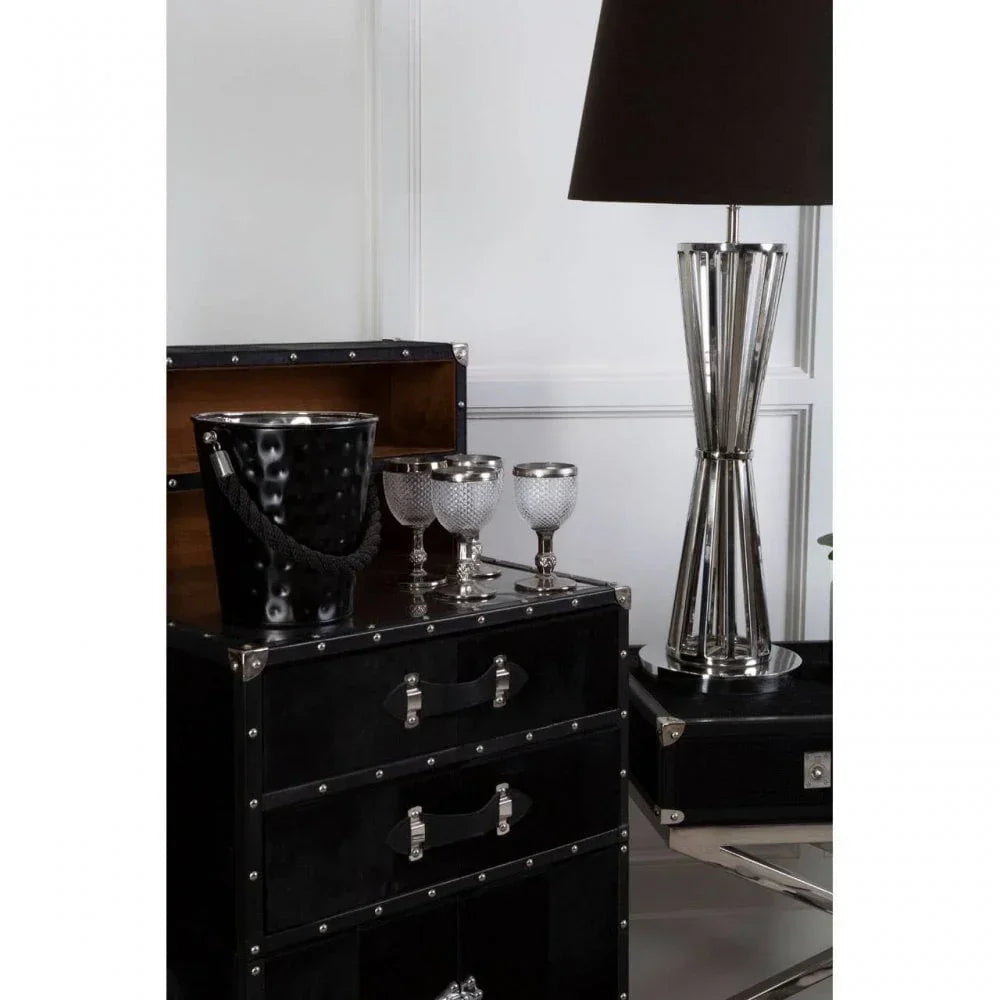 Black storage chest with silver accents, metal ice bucket, goblets, and modern table lamp