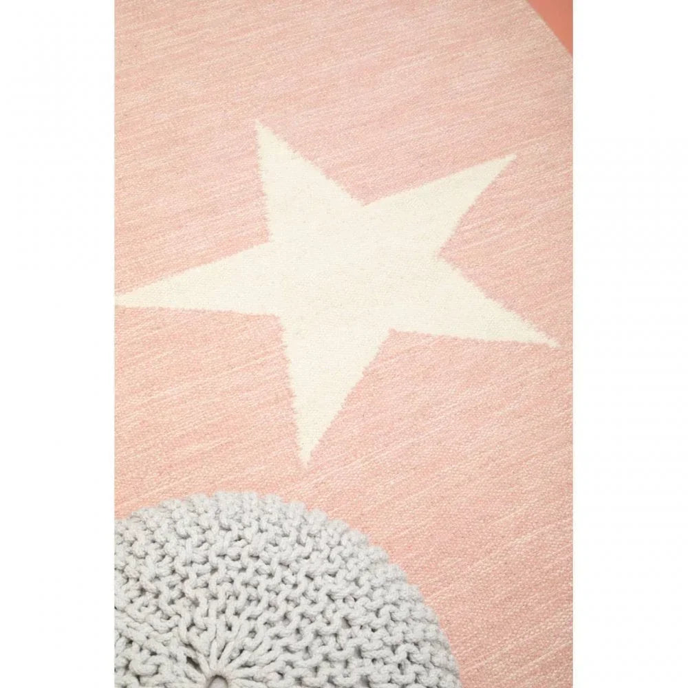 Pink area rug with white star design and chunky knit round footstool in corner