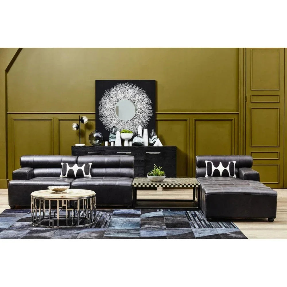 Modern black leather corner sofa with geometric cushions and coffee table on patterned rug