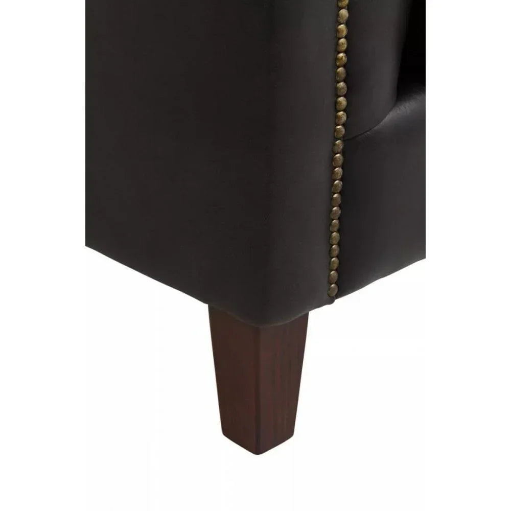 Black leather sofa corner with studded trim and dark wooden leg