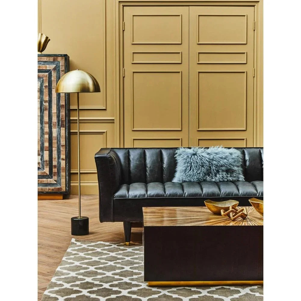 Black leather sofa with blue cushion in modern living room with patterned rug and wood coffee table