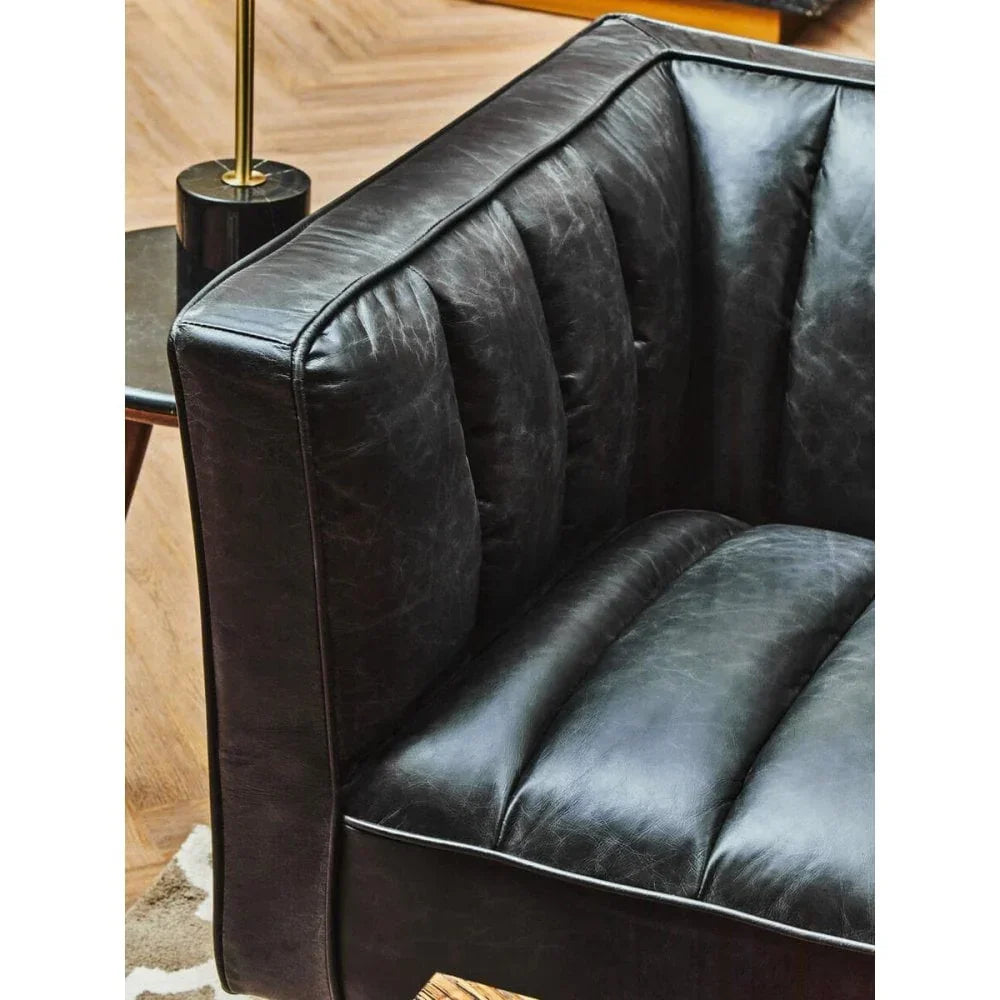 Close-up of black leather sofa corner with vertical stitching and deep seat cushion