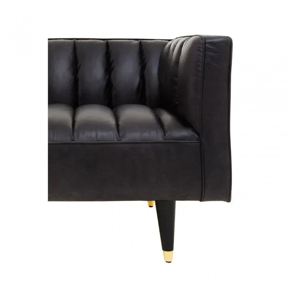 Black leather sofa corner with tufted seat and gold-tipped tapered legs