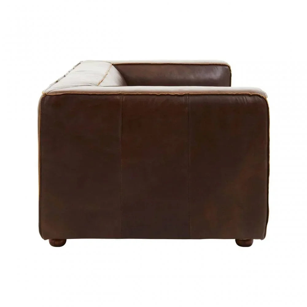 Side view of brown leather sofa with stitched panels and wooden feet