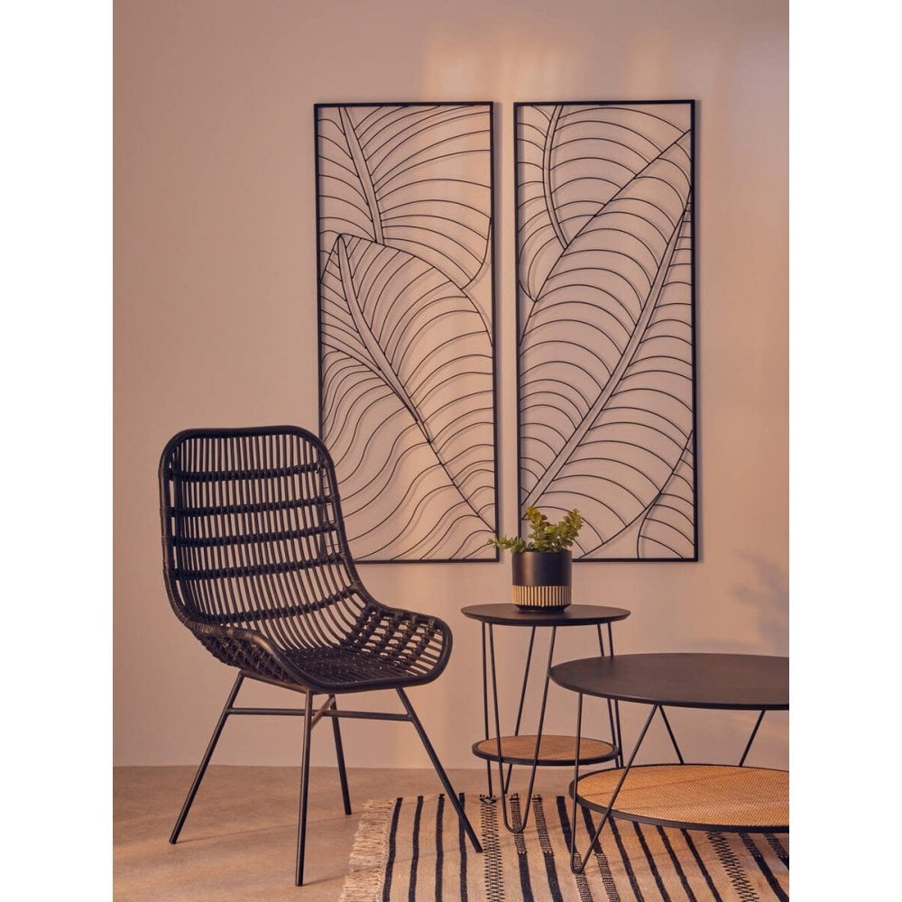 Black rattan accent chair with side tables and metal leaf wall art in modern living room