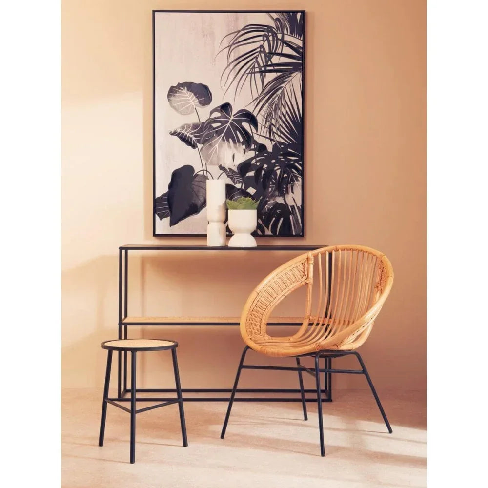 Rattan lounge chair with black metal legs beside console table and stool in modern living room
