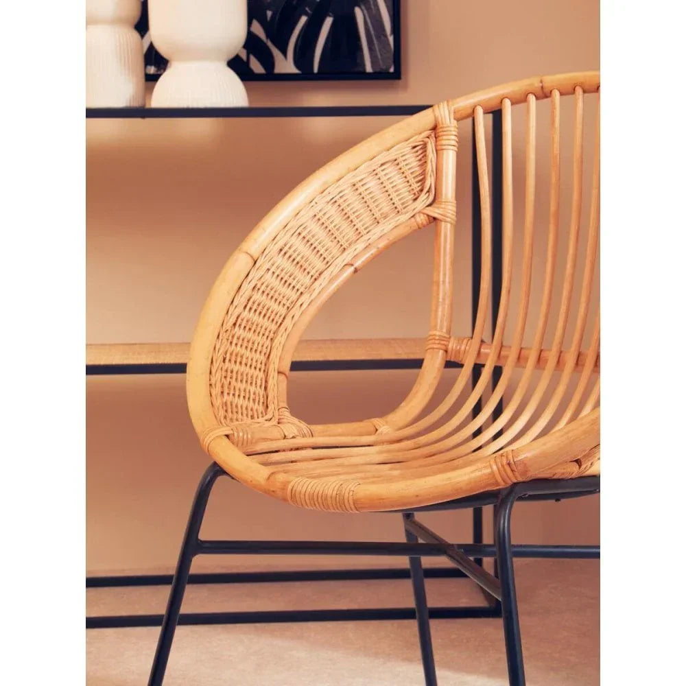 Curved rattan accent chair with black metal legs in modern living room setting