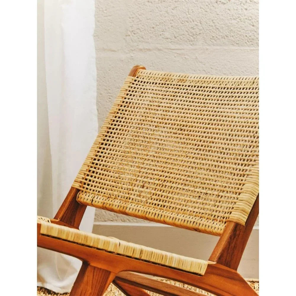 Close view of woven rattan lounge chair with wooden frame against neutral wall