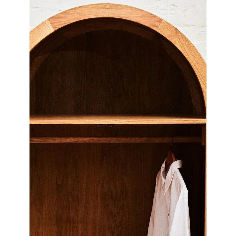 Wooden wardrobe with arched top, hanging rail, shelf, and white shirt on hanger