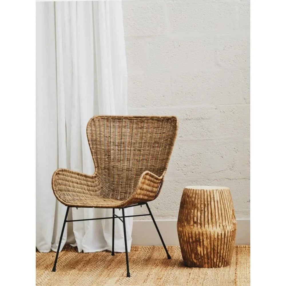 Natural rattan accent chair with black metal legs beside wooden side table on woven rug