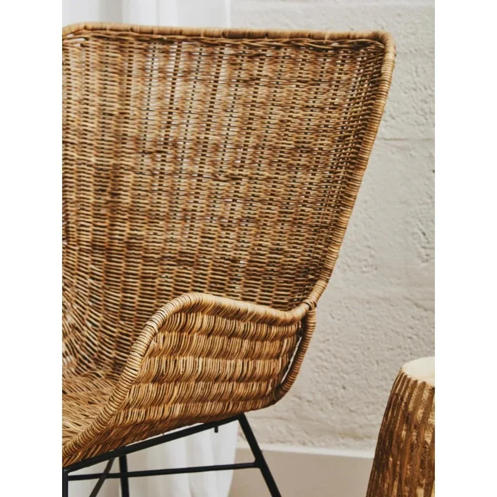 Close up of woven rattan armchair with high back and black metal legs
