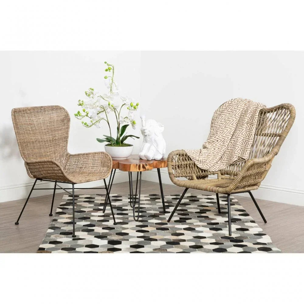 Rattan armchairs and wooden coffee table on geometric rug in modern living room setting