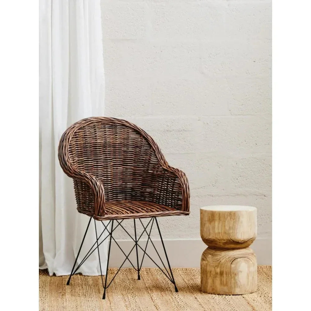 Brown rattan accent chair with metal legs beside a natural wood side table on woven rug