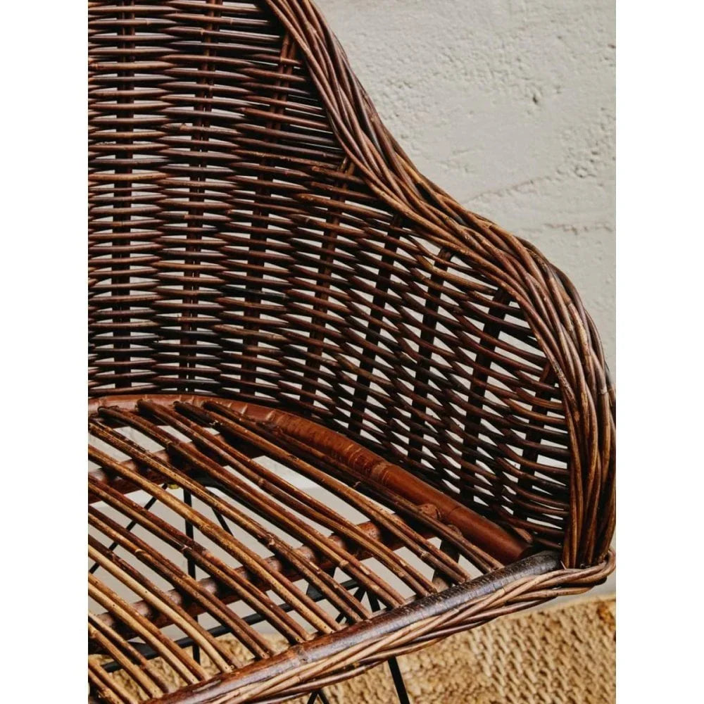 Close view of brown rattan chair with woven backrest and curved arm detail