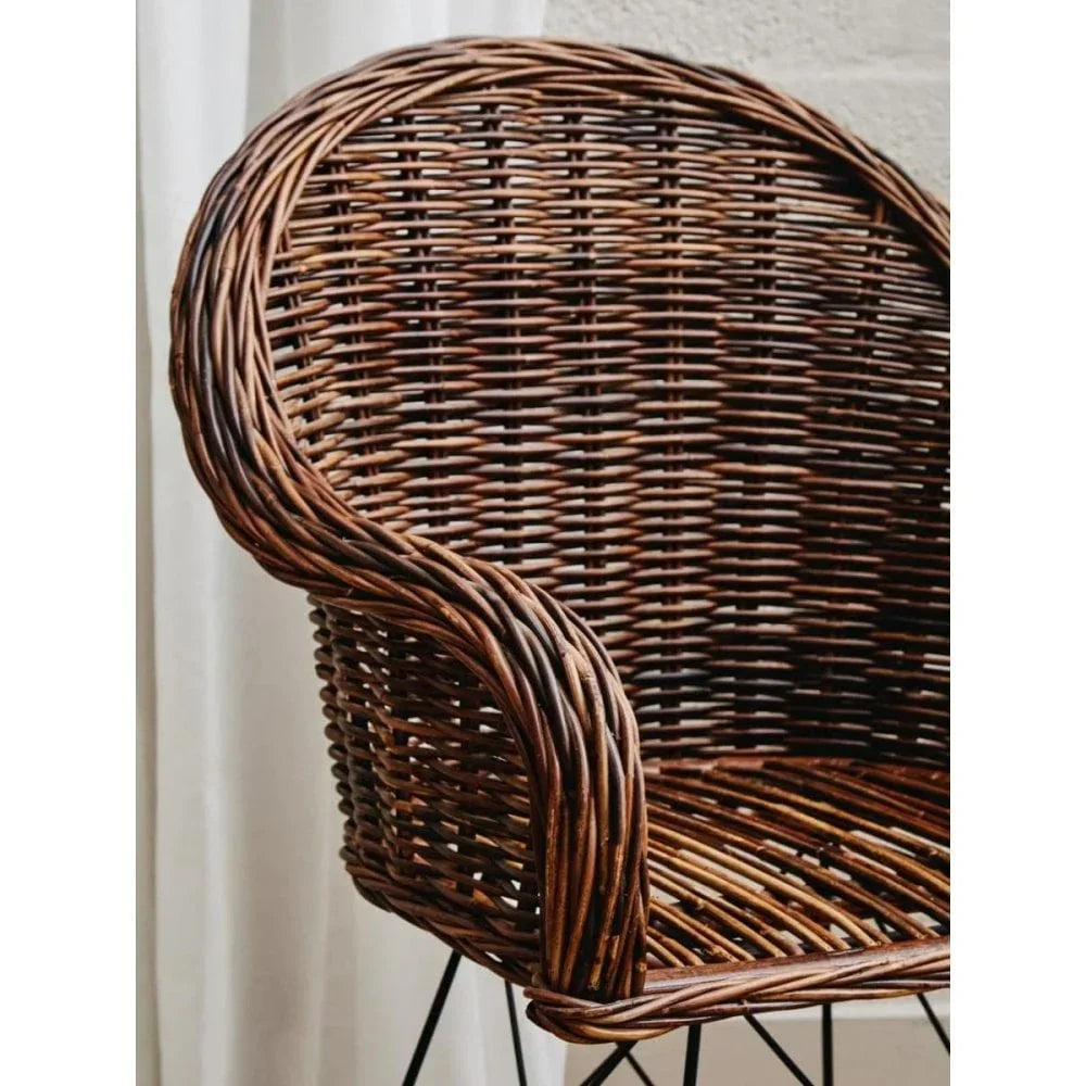 Brown wicker armchair with curved backrest and black metal legs