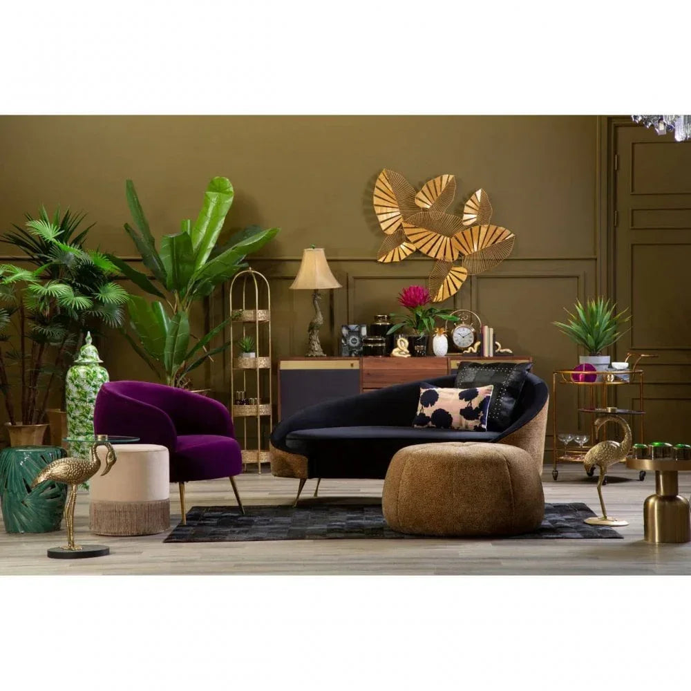 Modern living room with velvet armchair, curved sofa, ottoman, gold accents, indoor plants