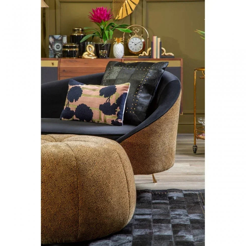 Curved tan and black accent chair with patterned cushions in modern living room setting