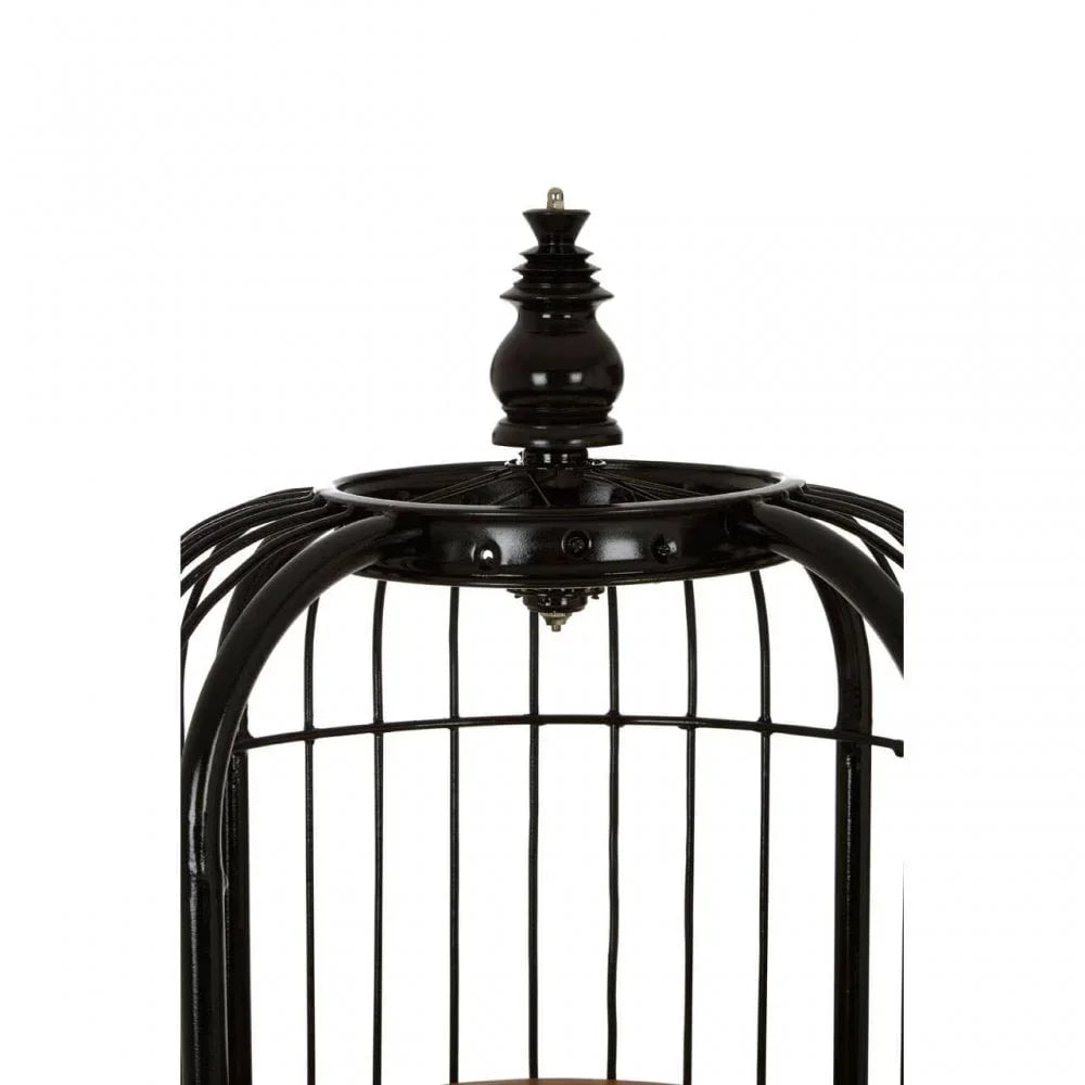 Black metal birdcage with decorative top finial and vertical bars, close up view