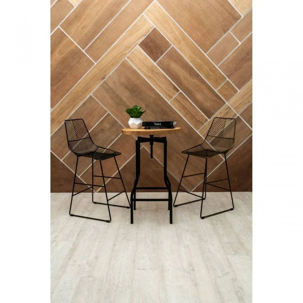 Black metal bar stools with wire seats and a wooden high table in modern dining area