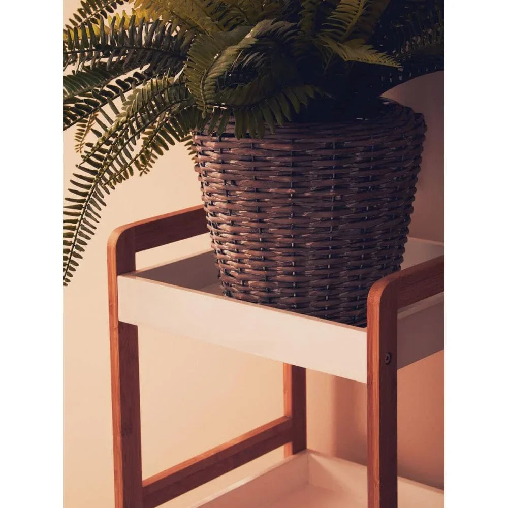 Wicker plant pot with fern on white wooden side table with natural wood frame