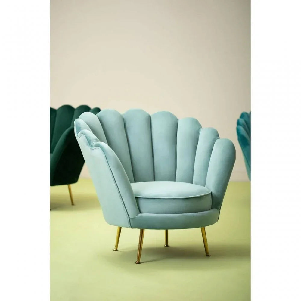Light blue velvet accent chair with scalloped backrest and gold legs on pale floor