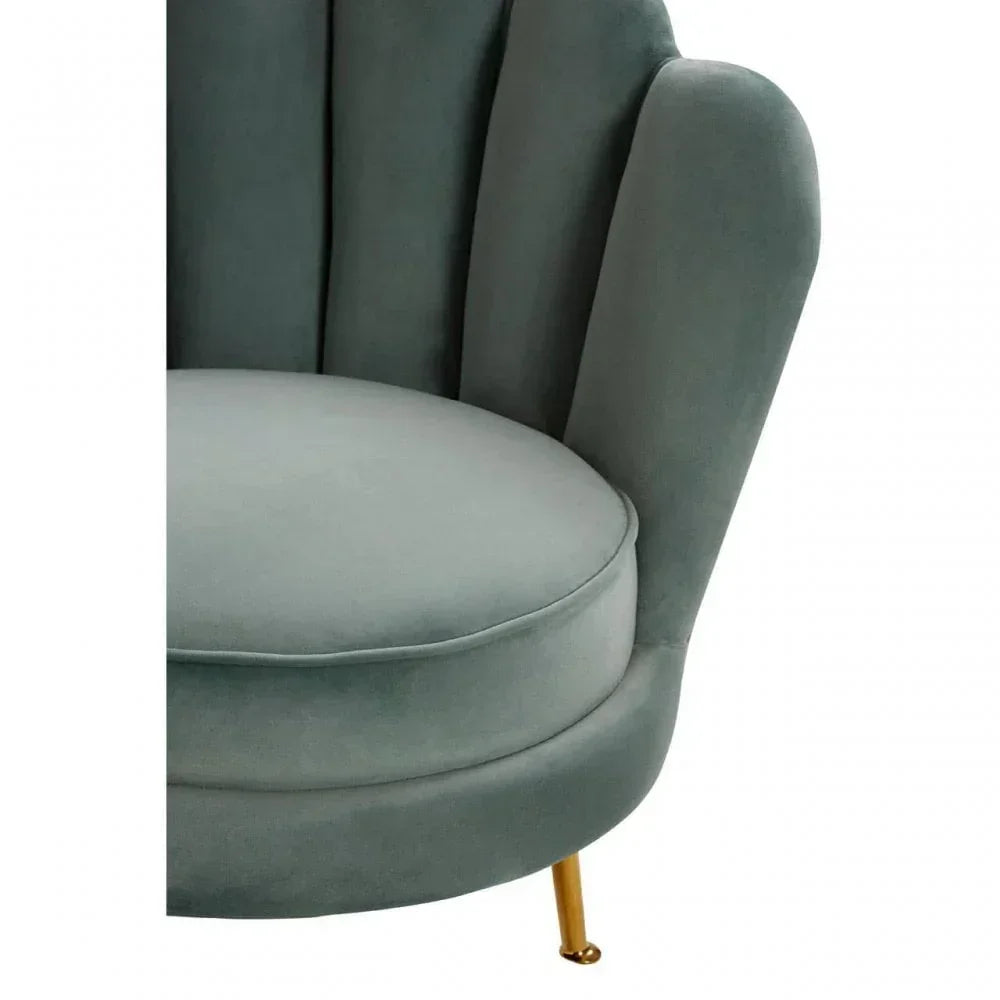 Close-up of green velvet accent chair with scalloped backrest and slim gold metal leg
