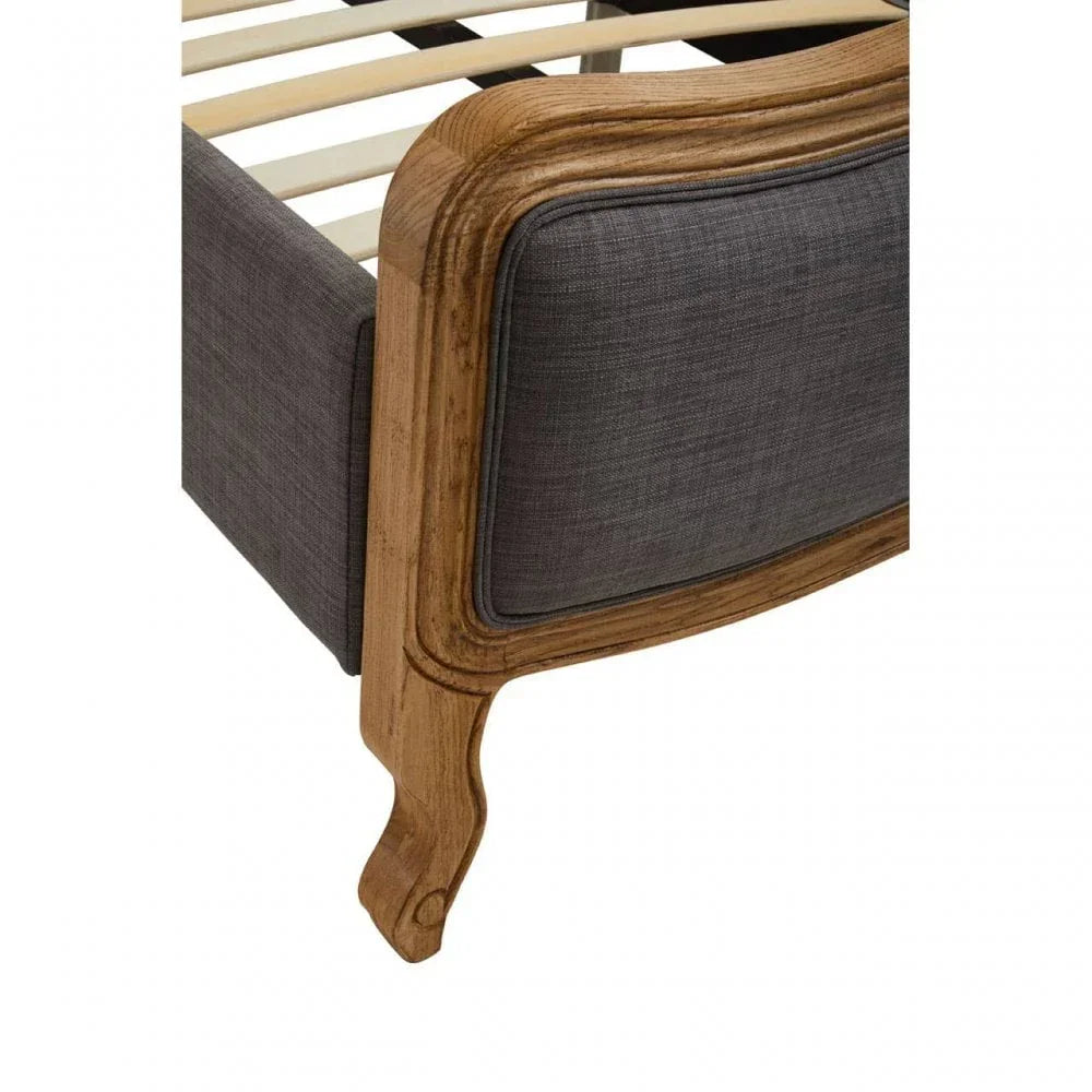 Close view of upholstered bed frame corner with wood finish and curved leg detail