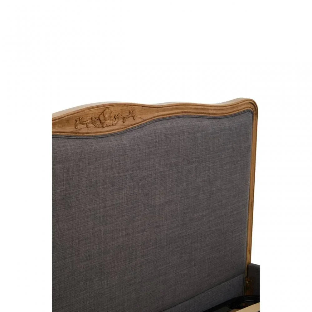 Grey upholstered headboard with carved wood trim and ornate floral detail