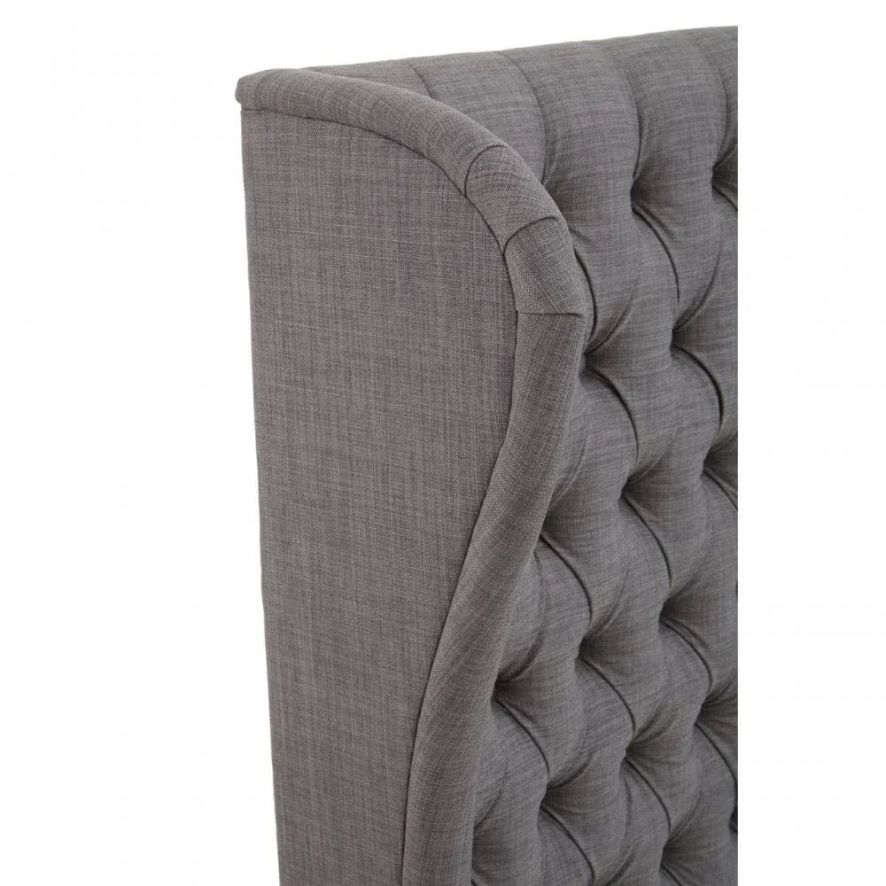 Close up of grey upholstered bed headboard with deep button tufting