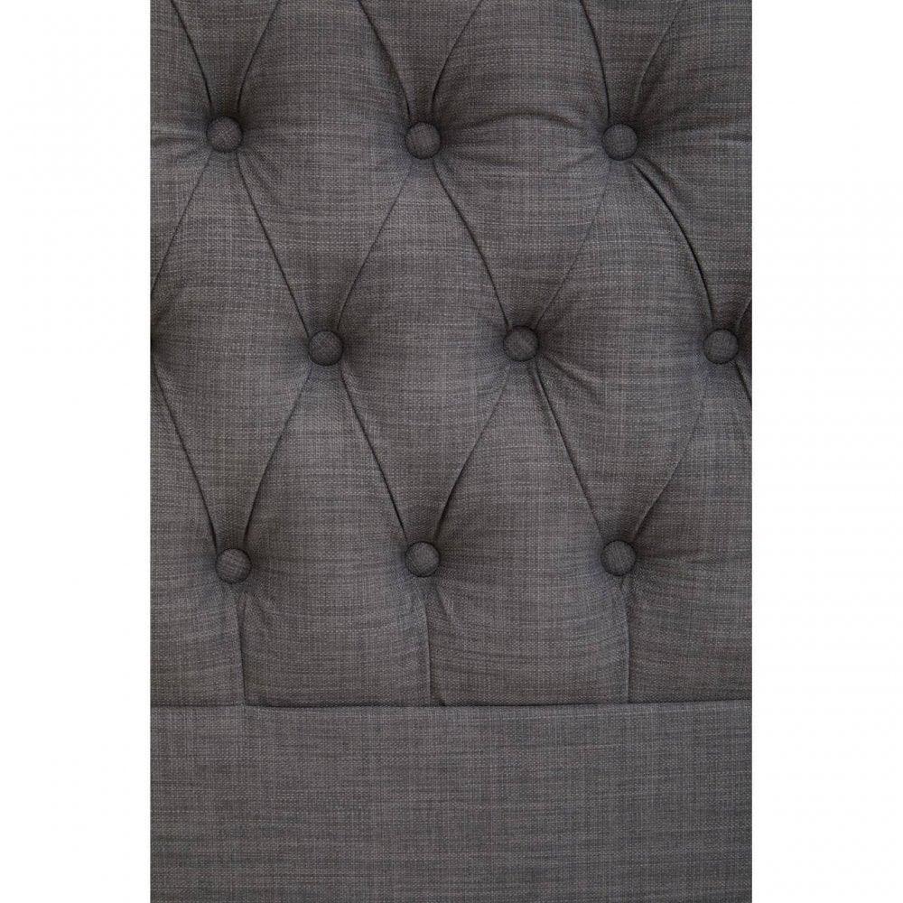 Grey fabric upholstered headboard with deep button-tufted diamond pattern close-up