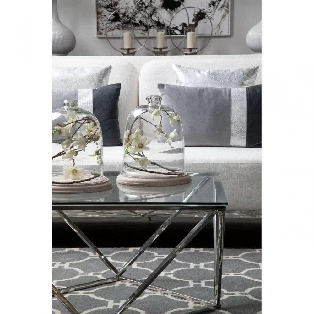 Glass coffee table with chrome legs, glass domes and white floral decor in modern living room