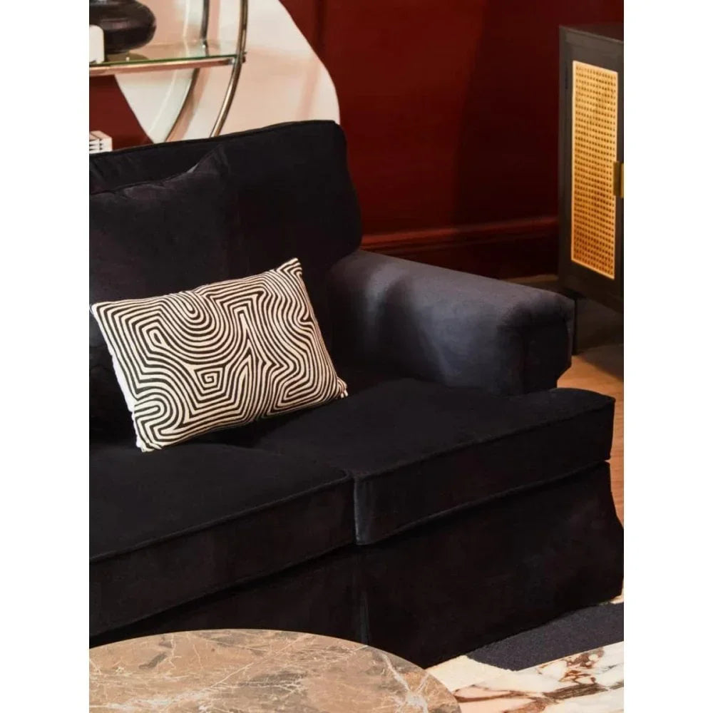 Black fabric sofa with patterned cushion beside marble coffee table in living room