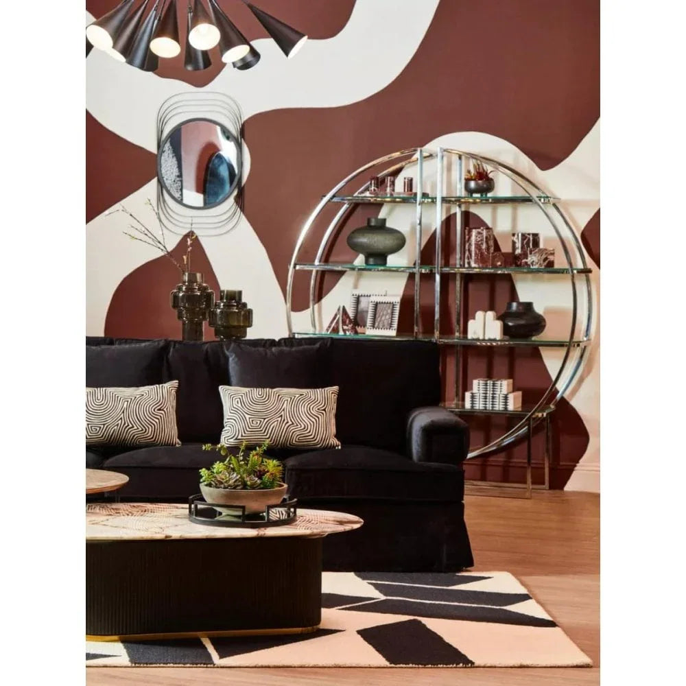 Modern black sofa with patterned cushions, round shelving unit, and abstract wall art