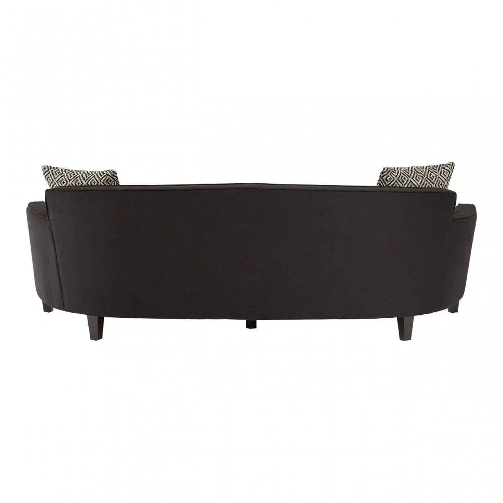 Curved black fabric sofa rear view with patterned scatter cushions and wooden legs