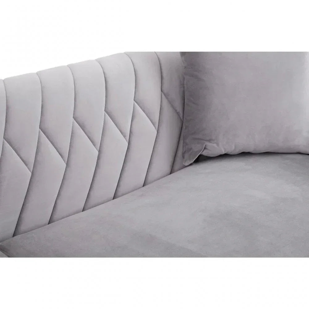 Light grey velvet sofa with quilted backrest and matching cushion, corner close-up