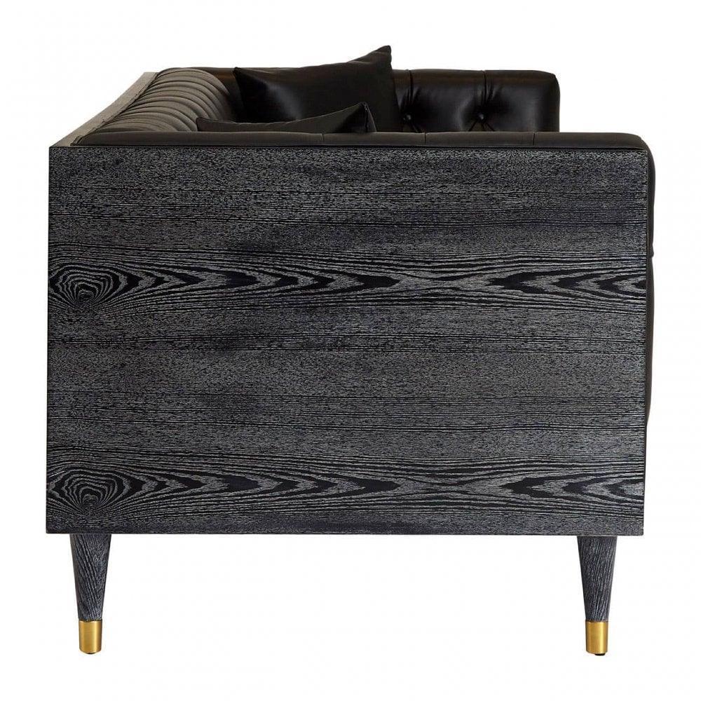 Black wood side panel of sofa with gold-tipped legs and tufted leather backrest