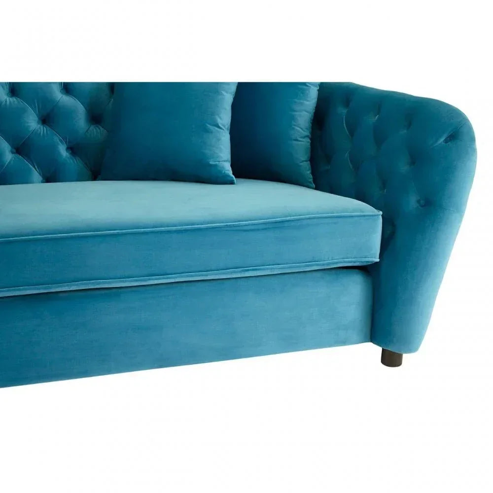 Blue velvet sofa with tufted backrest, curved armrest, and matching cushions