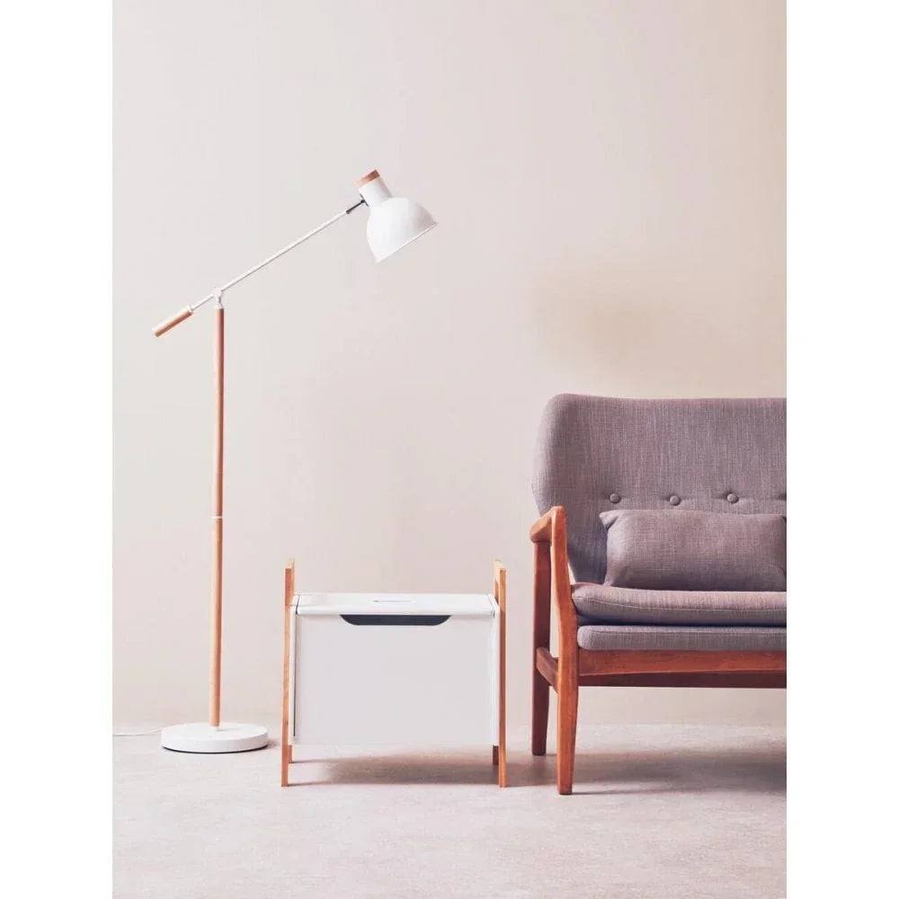 Modern grey fabric sofa with wooden frame, white floor lamp, and white storage box