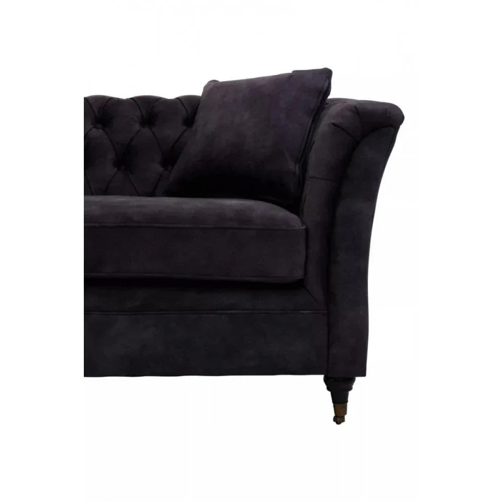 Dark velvet sofa corner with scroll arm, button tufting and loose cushion