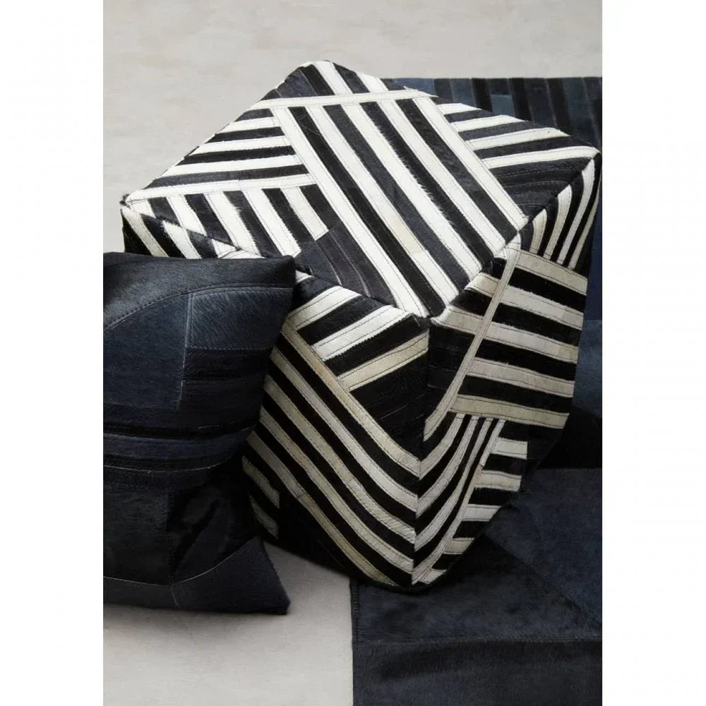 Black and white striped ottoman cube with geometric pattern next to black patchwork cushion