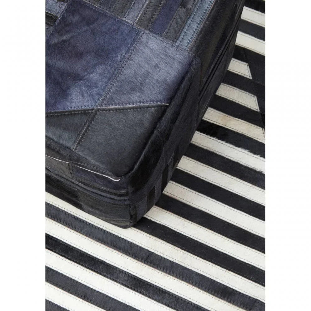 Black leather ottoman on striped black and white rug, close-up of stitching detail