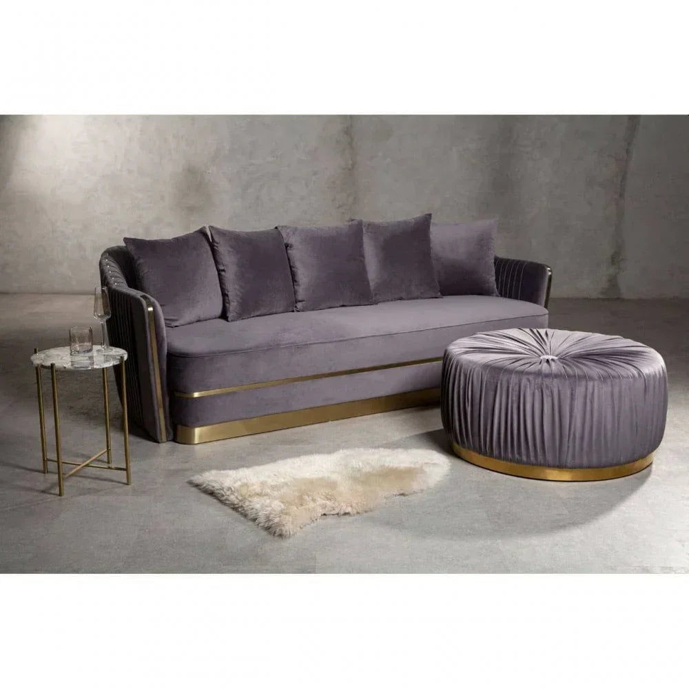Grey velvet sofa with four cushions and matching round ottoman in modern living room setting