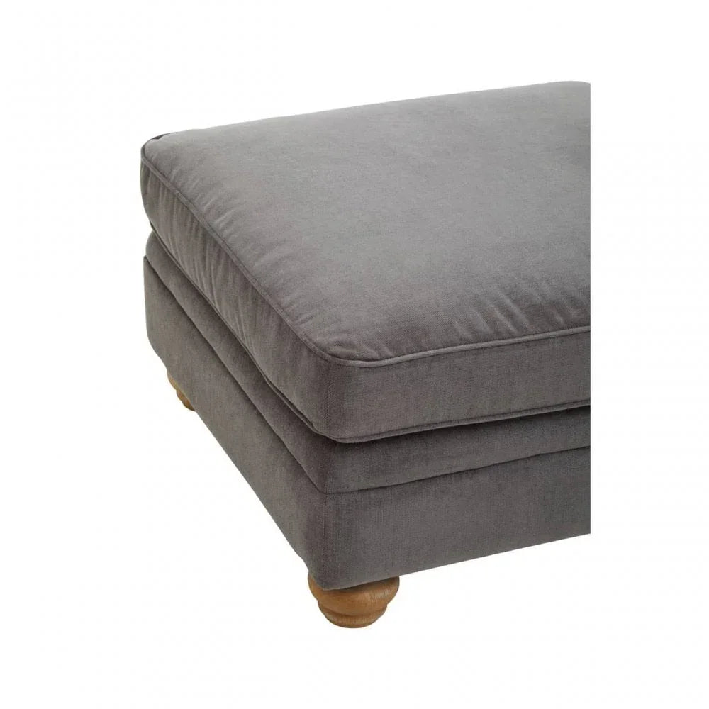 Grey fabric ottoman with wooden legs and plush cushion close-up