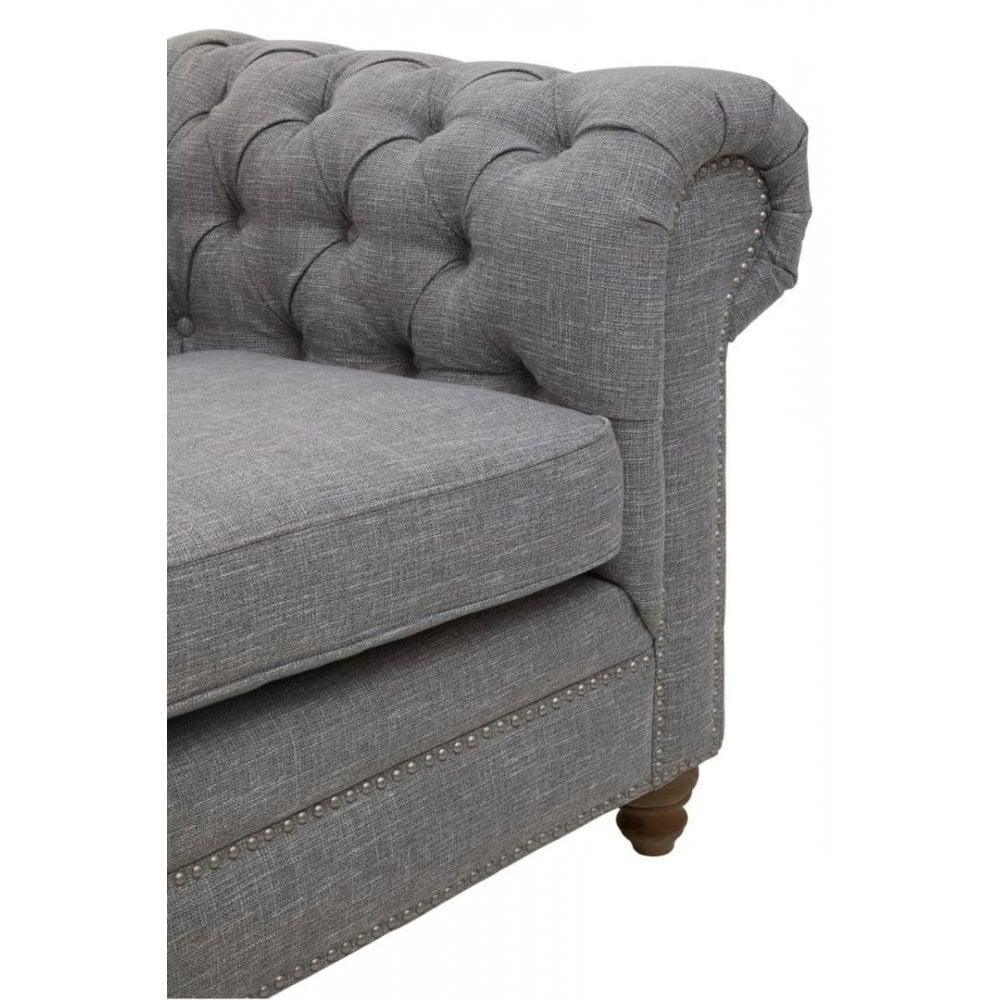 Grey fabric sofa with tufted backrest, studded trim and wooden leg, close-up view