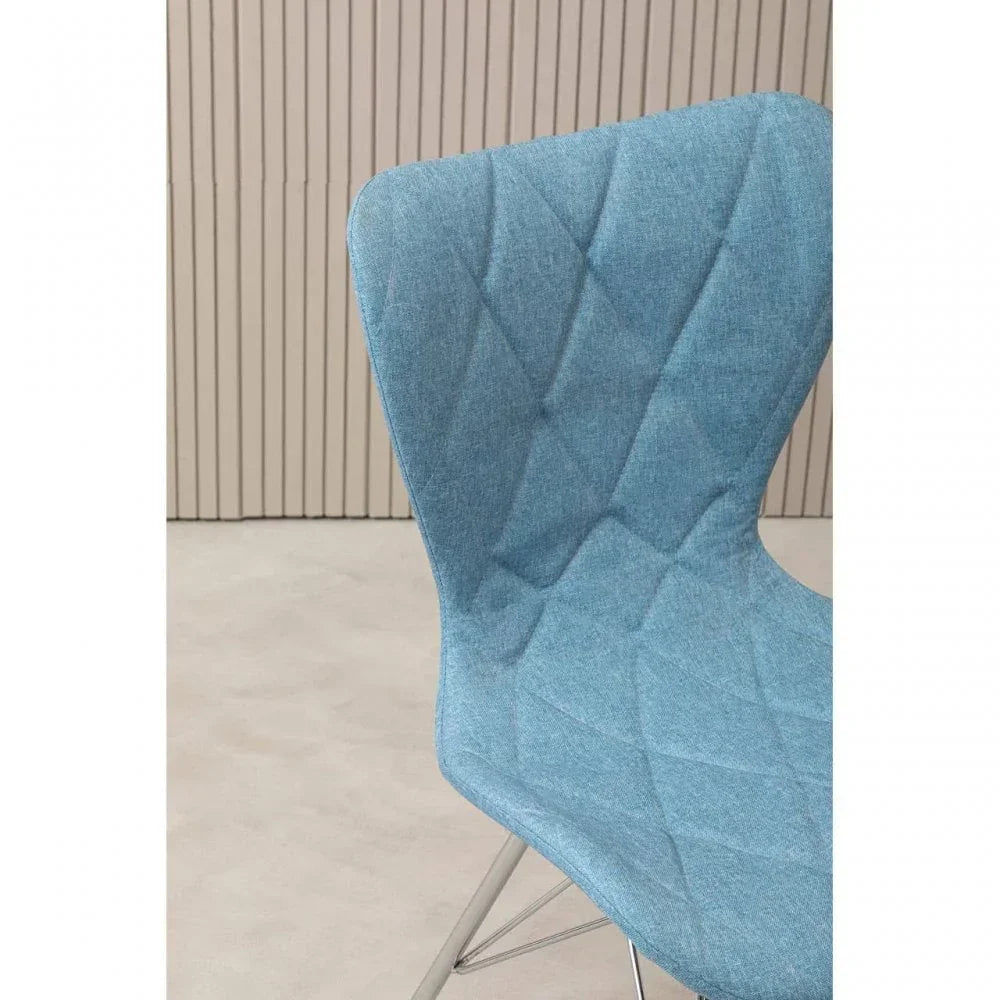 Closeup of blue fabric dining chair with diamond stitching and metal legs