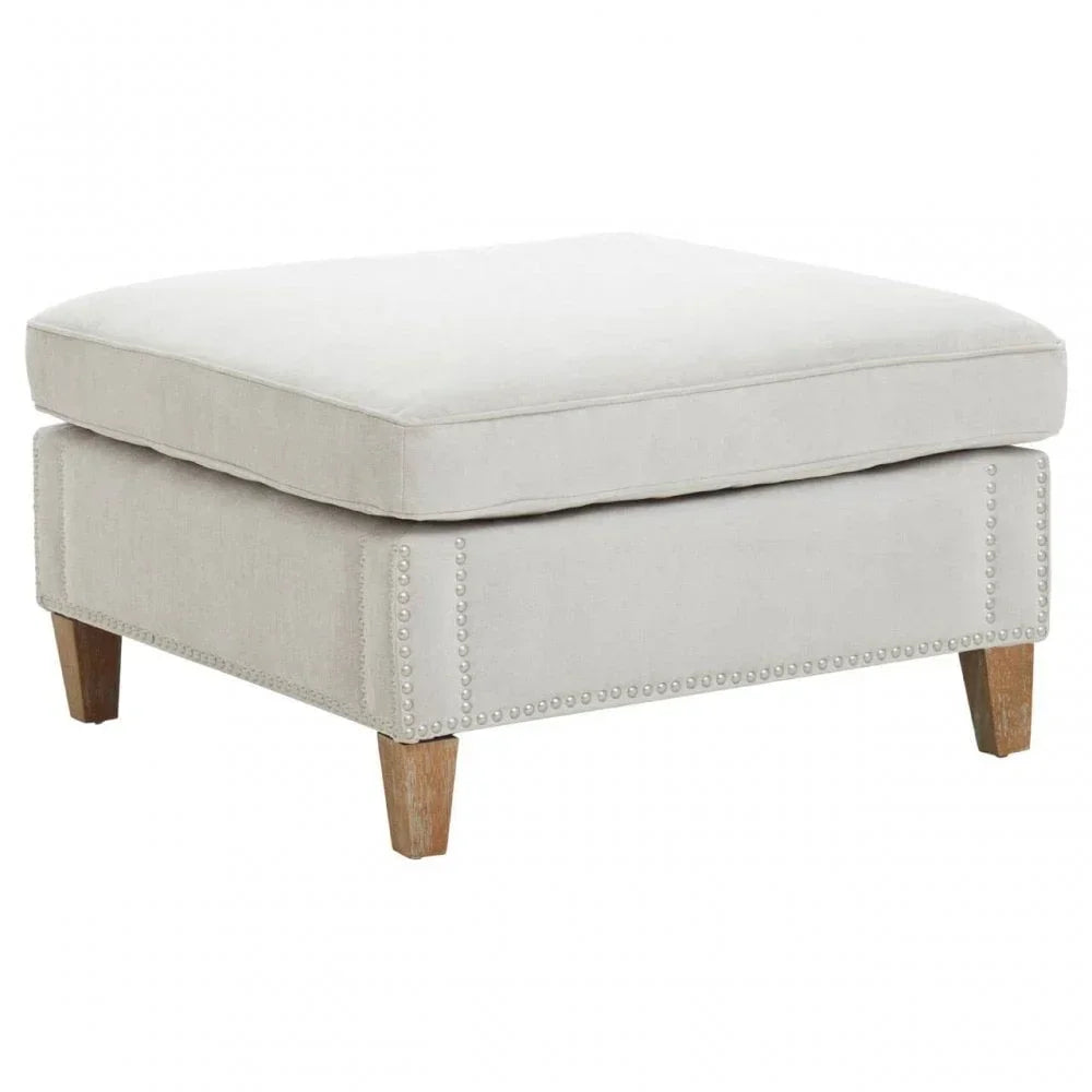 Beige fabric ottoman with nailhead trim and wooden legs, front angle view